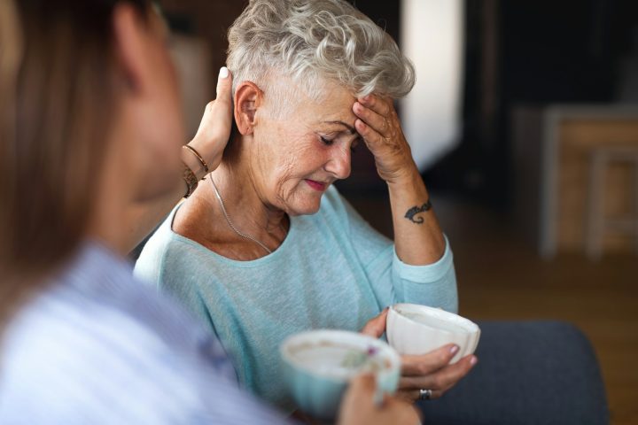 Adult daughter consoling unhappy senior mother and supporting her in struggle indoors at home
