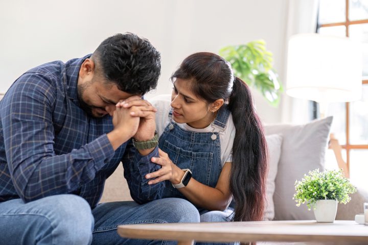 A young woman encourages and holds the hand of her worried husband. is having a hard time making